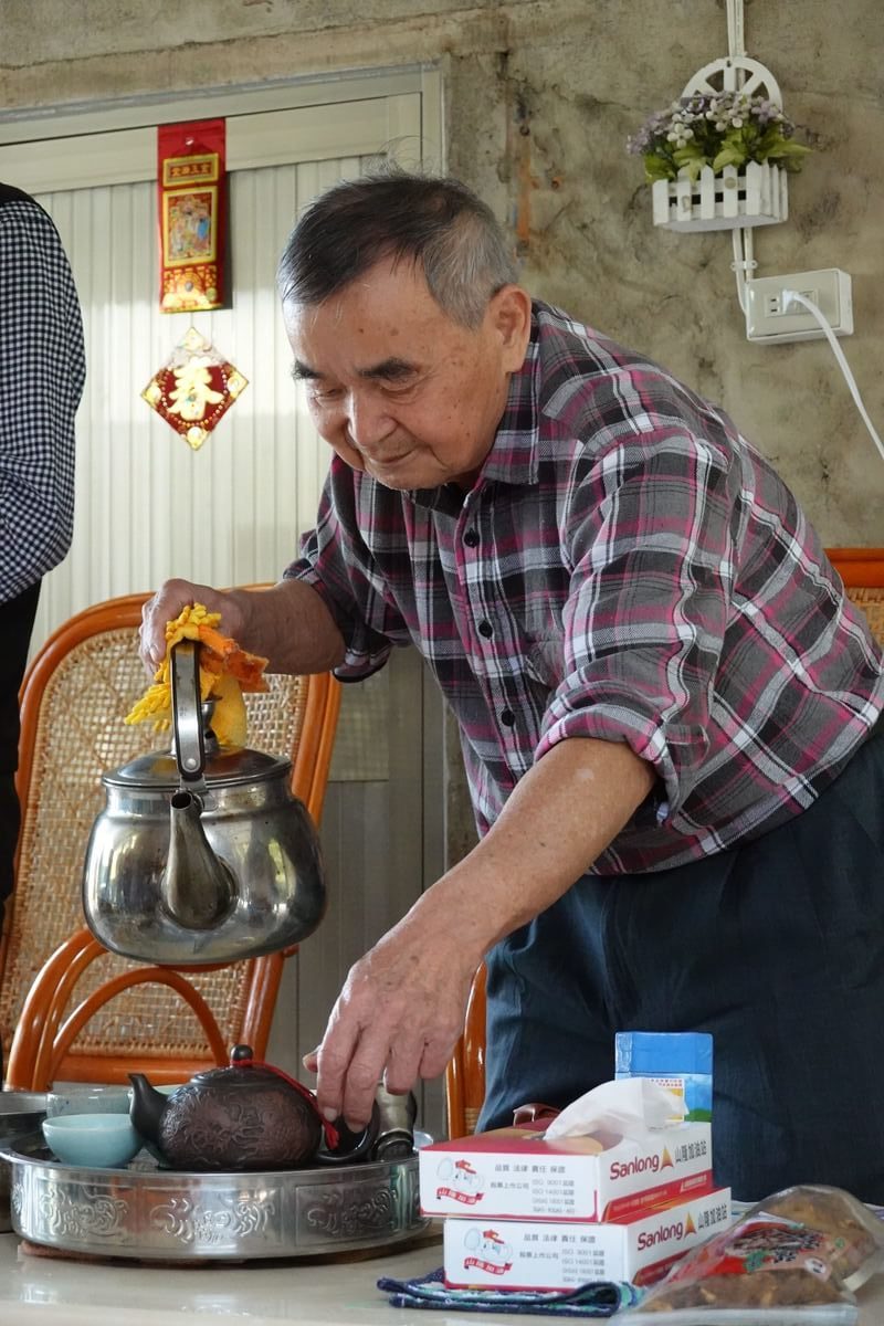 正在倒茶招待參與導覽的朋友們的邱瑞輝爺爺